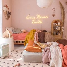 a bedroom with pink walls and lots of stuff on the floor, including blankets and pillows