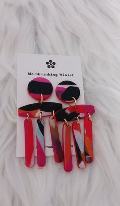 three pairs of pink, black and white earrings on top of a furnishing