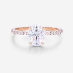 a rose gold engagement ring with an oval cut diamond in the center and pave set shoulders