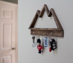 the key holder is made out of wood and has three key chains hanging from it