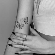 two women's hands with tattoos on their arms and one has a butterfly tattoo