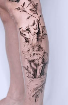 a woman's leg with a wolf and leaves tattoo on the side of her leg