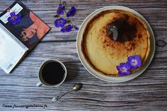 a pancake on a plate next to a cup of coffee and an open book