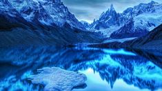 the mountains are covered in snow and blue hues as they reflect on the water