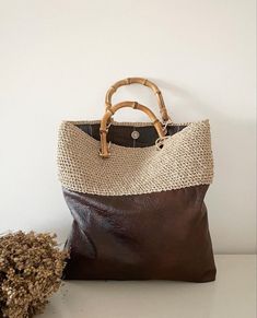 a brown and white purse next to a dried plant