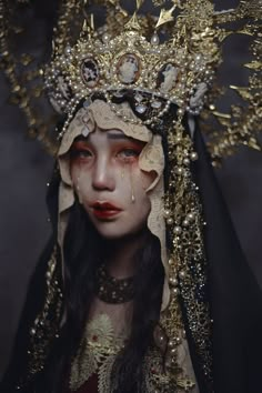 a woman wearing a crown with gold decorations on her head and black veil over her face