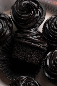 several chocolate cupcakes sitting on top of a white plate with black frosting