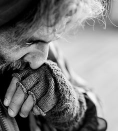 a person with their hand on his mitten and looking down at the ground in black and white