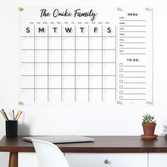 a desk with a calendar hanging on the wall above it and a potted plant next to it