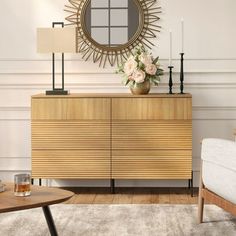 a living room with a couch, table and mirror on top of the dresser next to it