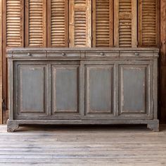 an old wooden chest with shutters on the wall and floor in front of it