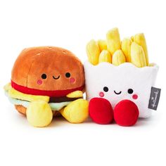 two stuffed animals sitting next to each other near a hamburger and french fries on a white background