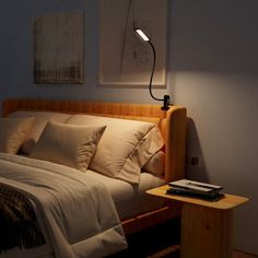 a bed with white sheets and pillows in a bedroom next to a lamp on the wall