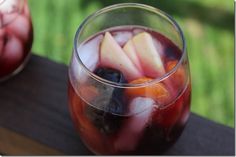 a glass filled with fruit sitting on top of a wooden table