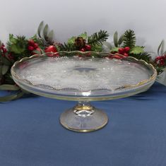 a glass platter on a blue table with holly and red berries in the background