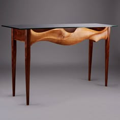 a wooden table with a glass top on it's legs and an abstract design