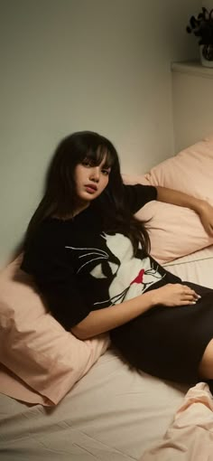 a woman laying on top of a bed next to a cat t - shirt dress