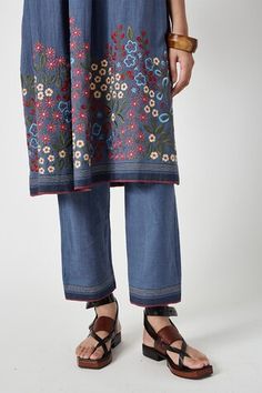 Blue kurta featuring floral embroidery on the hem and a striped pattern. Paired with a coordinating pant for a complete look., Fit: Relaxed Traditional Spring Pants With Printed Motifs, Traditional Floral Print Festive Bottoms, Traditional Embroidered Straight Kurta Bottoms, Traditional Wide Leg Sets With Floral Embroidery, Traditional Floral Embroidered Wide Leg Sets, Traditional Floral Print Bottoms For Spring, Traditional Spring Floral Print Bottoms, Cotton Chikankari Embroidery Straight Kurta Bottoms, Traditional Resham Embroidered Bottoms For Spring