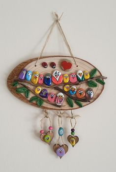 a wooden wall hanging with colorful owls and hearts on it's side, attached to a white wall