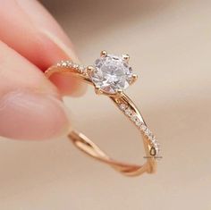 a woman's hand holding an engagement ring with a white diamond in the middle