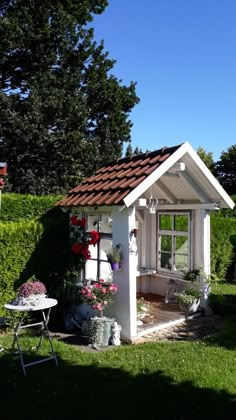 a small white shed sitting on top of a lush green field