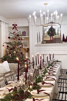 a dining room table set for christmas dinner with candles and decorations on the table top