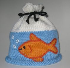 a knitted hat with an orange fish on the front and blue bottom, sitting on a white surface