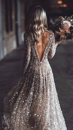 the back of a woman's dress with long sleeves and sequins on it