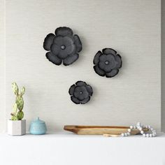 three black flowers on a white wall above a shelf