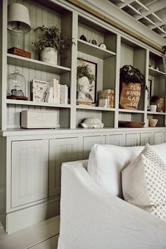 a living room filled with white furniture and lots of open shelving unit space next to a couch