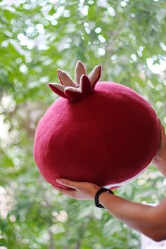 a woman holding a red hat in front of trees