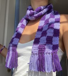 a woman wearing a purple and white knitted scarf with tassels on the ends