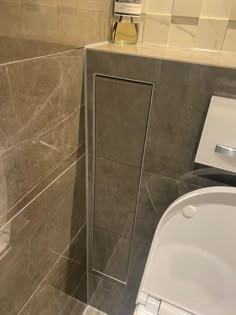 a bathroom with a toilet and shower stall in it's corner, next to a tiled wall