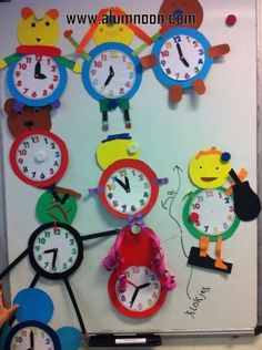 a group of children's clocks hanging on the wall in front of a whiteboard