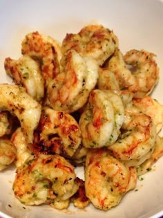 a white bowl filled with cooked shrimp on top of a table