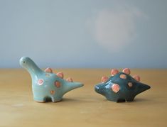 two ceramic dinosaurs sitting next to each other on a table