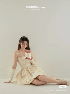 a woman in a dress sitting on the floor holding a cake