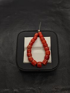 a red beaded necklace sitting on top of a black leather chair next to a white button