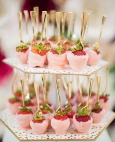 small desserts with strawberries on them are arranged in three tiered trays