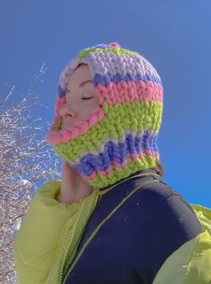 a woman wearing a multicolored knitted hat with a pink, blue, and green stripe