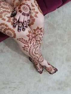 the legs and feet of a woman with henna on her body, sitting down