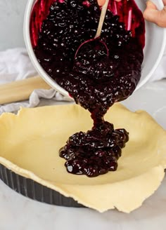 someone is pouring blueberry sauce into a pie crust