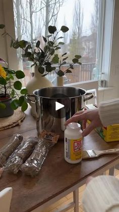 a person is preparing food on a table with flowers in the window sill behind them