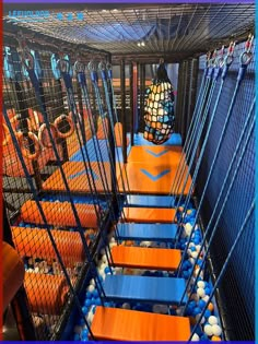 an indoor play area with blue and orange balls in the caged enclosures for children