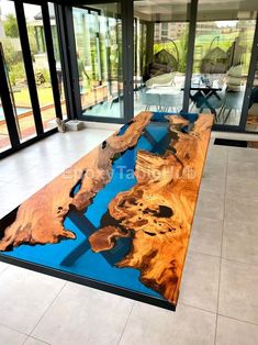 a large wooden table sitting on top of a tile floor next to a glass wall