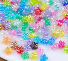 many different colored beads are on a white plate and next to it is a flower shaped bead