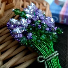 a bunch of purple and green flowers sitting on top of a table next to a wicker basket