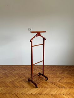 a wooden stand with a coat hanger on it's side in an empty room