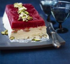 a piece of cake sitting on top of a plate next to a wine glass and spoon