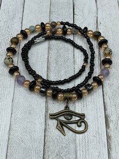 "🌟 Welcome to our shop! 🔥 ✨ Our handmade \"I am Protected\" Waist Beads with Eye of Horus Charm are the perfect blend of tradition and spirituality. ✨ 💎 Made with the highest quality materials and crafted with care, our waist beads are stretchy and come with a clasp for easy wearing and adjusting. They feature a beautiful Eye of Horus charm and multiple crystals including Amethyst, Hematite, Jasper, and Tiger Eye. Each of these crystals holds powerful energy that can enhance your spiritual jo Oval Beaded Amulet Jewelry, Symbolic Round Gemstone Beads Jewelry, Adjustable Beaded Spiritual Jewelry, Beaded Amulet Jewelry For Meditation, Beaded Amethyst Gold Jewelry, Spiritual Amethyst Round Bead Jewelry, Meditation Beaded Amulet Jewelry, Symbolic Gemstone Beads Jewelry, Adjustable Gold Beads, Gems, And Cabochons